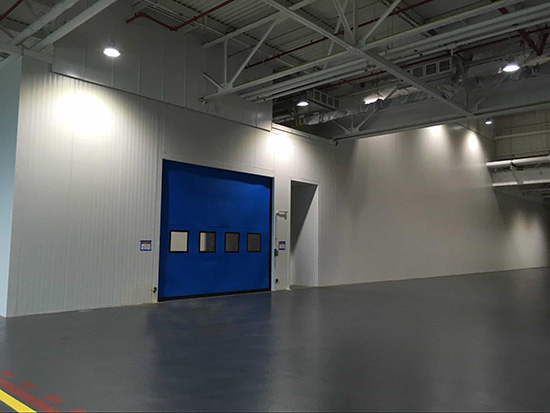a modular wall system with a blue garage door in a large warehouse